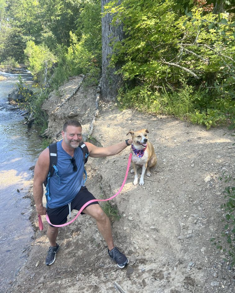 Dr. Pelton hiking with his dog by the creek